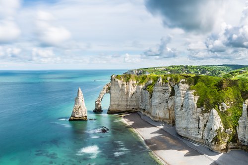Kreidefelsen von Étretat an der Küste der Normandie, Frankreich, mit bewölktem Himmel und ruhiger See im Hintergrund.