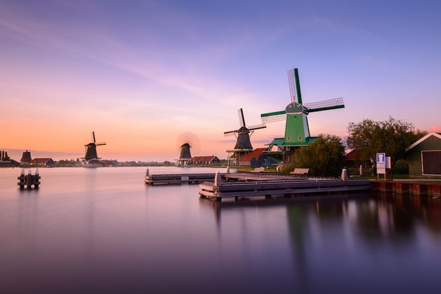 Traditionelle niederländische Windmühlen und Holzhäuser am Wasser in Zaanse Schans während des Sonnenuntergangs