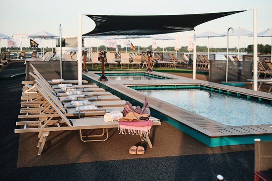 Das Sonnendeck der A-ROSA SENA bei Tageslicht mit Swimmingpool und Kids-Pool sowie zahlreichen Liegestühlen.