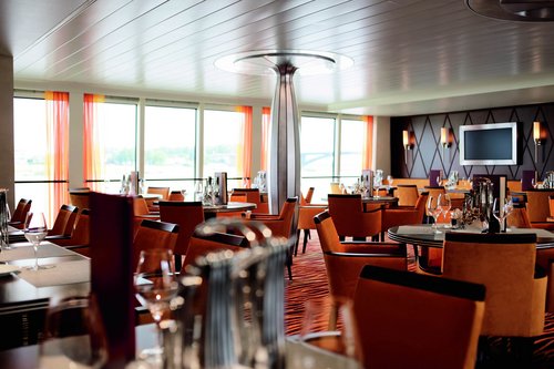 Stilvoll eingedeckter Restaurantbereich der A-ROSA AQUA und BRAVA mit bodentiefen Fenstern und Blick auf einen ruhigen Fluss.